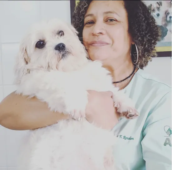 Profissional da equipe Vida Animal segurando um cãozinho branco no colo